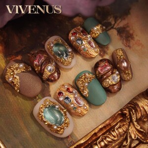 May include: An assortment of ornate, bejeweled nail art designs. The nails feature gold filigree, pearls, and colorful gemstones. Some nails are a muted green, while others are neutral tones. The word "VIVENUS" is at the top.