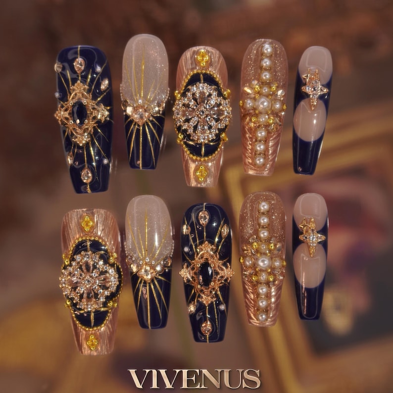 May include: A collection of ten long, coffin-shaped false nails. Designs include navy blue, gold, and pearl embellishments. Some nails have detailed gold filigree, others a gradient effect. The brand name "VIVENUS" is displayed at the bottom of the image.