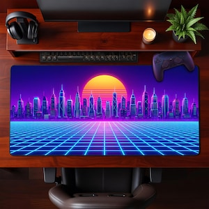 May include: A large rectangular mouse pad featuring a retro cityscape design with a vibrant sunset, grid, and neon-style buildings. The color scheme includes shades of purple, blue, and orange. A keyboard, controller, and headphones are visible.