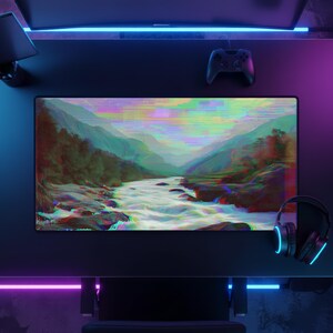 Peut inclure: Configuration de bureau de jeu noire avec un grand &eacute;cran affichant un paysage de rivi&egrave;re et de montagnes en glitch art. Une manette et un casque noirs sont &eacute;galement pr&eacute;sents, avec un &eacute;clairage d'appoint bleu et violet.