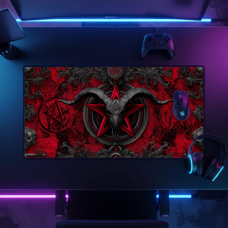 May include: A rectangular gaming mouse pad with a red background and a black goat skull design. The design includes a pentagram and ornate scrollwork. A black mouse, controller, and headset are also visible.