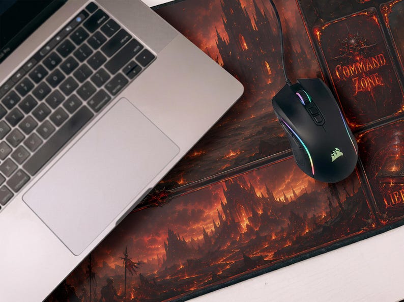 May include: A laptop and a black gaming mouse with rainbow LED lights sit on a large mousepad. The mousepad features a fiery fantasy landscape design with the words "Command Zone".