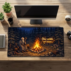 May include: A rectangular mousepad with a forest scene, campfire, and an elderly man with a staff. The text "Stay awhile and listen" is in gold. The mousepad is on a wooden desk with a computer monitor and accessories.