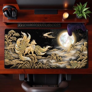 May include: A large rectangular desk mat featuring a golden nine-tailed fox standing on a mountain, set against a night sky with a full moon. The design incorporates gold and black tones with a Japanese aesthetic. A controller rests on the mat.