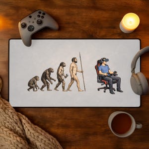 May include: A gaming mousepad with an evolution of man graphic, transitioning from ape to a person in VR. A gray controller, headphones, a candle, and a mug of tea are on a wooden surface.