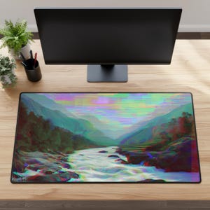 Peut inclure: Tapis de bureau rectangulaire avec un paysage de rivi&egrave;re dans une vall&eacute;e, avec un effet de glitch. Le tapis a une bordure noire et est pos&eacute; sur un bureau en bois. Un &eacute;cran d'ordinateur, des plantes et des accessoires de bureau sont &eacute;galement visibles.