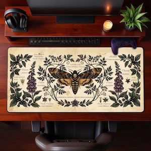 Könnte beinhalten: Eine rechteckige Schreibtischunterlage mit einer botanischen Illustration im Vintage-Stil, die in der Mitte einen Totenkopfschwärmer zeigt, umgeben von detaillierten Zeichnungen von Fingerhut und Tollkirsche mit wissenschaftlichen Beschriftungen.