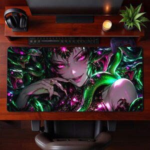 May include: A rectangular desk mat featuring a vibrant digital illustration of a character with glowing pink eyes and sharp features, surrounded by multiple green snakes with luminous pink accents. The artwork displays a dark, high-contrast color palette.