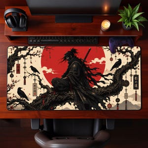 May include: A rectangular desk mat featuring a central illustration of a ninja in black robes sitting on a gnarled tree branch against a large red sun. The design includes black crows, hanging decorative charms, and Japanese kanji characters.