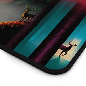 May include: A decorative mouse mat with a stylized illustration of deer in a forest setting. The design incorporates teal and purple stripes, with a black border. The artwork evokes a vintage, outdoorsy aesthetic.