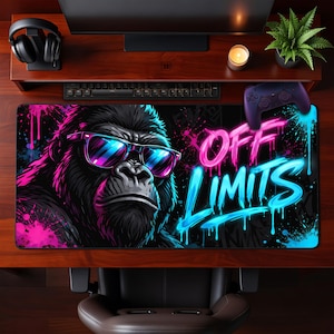 Puede incluir: Alfombrilla de ratón para juegos rectangular negra con un gorila con gafas de sol. El texto "OFF LIMITS" en rosa y azul neón. El diseño presenta salpicaduras de pintura.