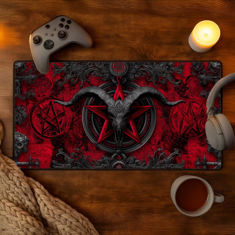 May include: A red and black gaming mousepad featuring a goat skull within a red pentagram. The design includes ornate, gothic-style borders and pentagrams. A gray game controller, headphones, and a lit candle are visible.