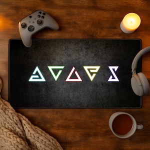 Può includere: Un tappetino per mouse da gioco rettangolare nero con una superficie strutturata, con cinque simboli geometrici illuminati in bianco, verde, rosso, giallo e viola. Sono visibili un controller di gioco grigio e delle cuffie.