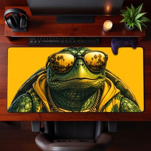May include: A rectangular desk mat featuring a graphic illustration of a green turtle wearing black sunglasses and a yellow hoodie with a gold chain. The sunglasses reflect a palm tree-lined street scene. The background is a solid bright yellow.