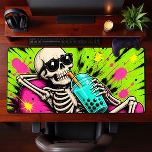 May include: A rectangular mouse pad featuring a cartoon skeleton wearing sunglasses and drinking a boba tea. The background is bright green with pink and yellow splatters. The skeleton is wearing a pink shirt.