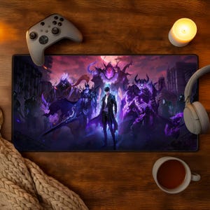 May include: A rectangular gaming mousepad featuring a fantasy illustration with a central figure in a black coat, surrounded by dark figures and a cityscape. The color palette includes shades of purple, black, and white. A gray game controller, headphones, and a cup of tea are also visible.