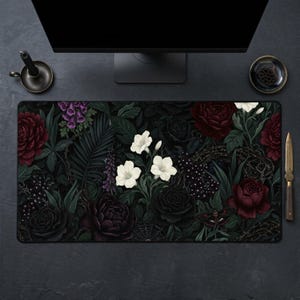 Op de afbeelding: Een rechthoekige muismat met een donker bloemenontwerp. De afbeelding toont bordeauxrode, zwarte en witte bloemen, met groene bladeren. Een mot en een spinnenweb zijn ook zichtbaar. Het thema is gotisch.