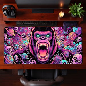 May include: A rectangular desk mat featuring a vibrant, psychedelic illustration of a roaring gorilla head at the centre, surrounded by floating skulls, alien creatures, and colourful planets in shades of neon pink, purple, blue, and yellow.