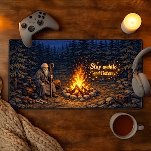 Puede incluir: Alfombrilla de rat&oacute;n rectangular con una ilustraci&oacute;n pixelada de un anciano junto a una fogata en un bosque. Se muestra el texto "Stay awhile and listen". Tambi&eacute;n se ven un mando de juego gris y unos auriculares.