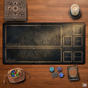 Könnte beinhalten: Eine schwarze und goldene Spielmatte mit den Wörtern "Battlefield" und "Lands" aufgedruckt. Die Matte hat Felder für Karten und Würfel und ist von anderem Spielzubehör umgeben, darunter eine Kerze, Würfel und ein Kartenspiel.