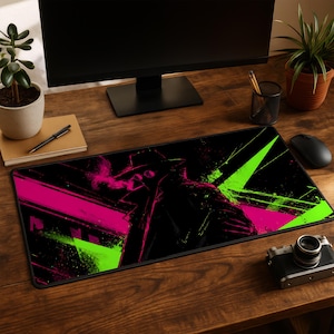 May include: Black rectangular mouse mat with a stylized illustration of a figure in a hat and coat, smoking. The design incorporates neon pink and green geometric shapes against a black background. A computer monitor, mouse, and camera are visible.