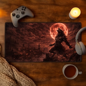 May include: A gaming mousepad with a dramatic illustration of a werewolf howling at a red moon. The scene is set against a dark, ominous sky with a cityscape in the background. A gray game controller, headphones, a candle, and a cup of tea are also visible.