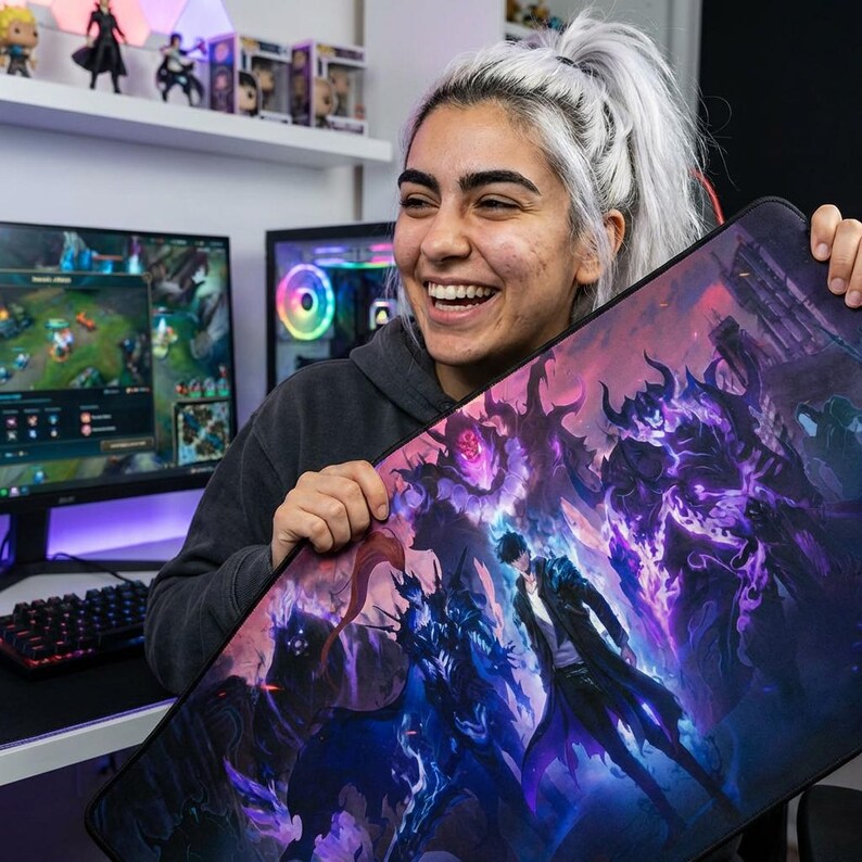 May include: Large rectangular gaming mouse pad featuring a fantasy illustration with purple and blue hues. The artwork depicts figures in a dark, dramatic scene. The mouse pad is designed for use with a computer and keyboard.