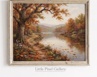 May include: A framed landscape painting depicting an autumn scene with a large tree on the left, a winding dirt path, and a calm river reflecting the orange and brown foliage. The artwork is enclosed in a light-colored wooden frame with visible grain.