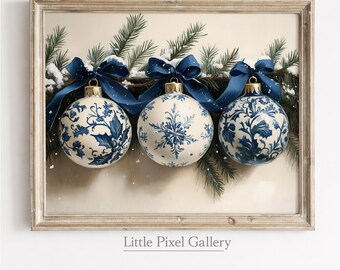 May include: A framed print featuring three white and blue Christmas ornaments with intricate floral designs. The ornaments are adorned with dark blue ribbons and hang from a garland of pine branches dusted with snow. The frame is a light, natural wood color.