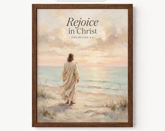 Könnte beinhalten: Ein gerahmter Kunstdruck mit einer Figur in einem langen Gewand, die an einem Sandstrand steht und auf einen ruhigen Ozean bei Sonnenuntergang blickt. Der Text lautet Rejoice in Christ PHILIPPIANS 4:4. Die Farbpalette umfasst sanfte Beige-, Hellblau- und Pfirsichtöne.