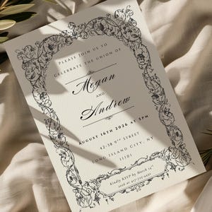 May include: Ivory wedding invitation with black ornate floral border. The invitation reads "Megan and Andrew" and includes the date August 16th, 2026. The RSVP information is also included. The invitation is on a cream-colored background.