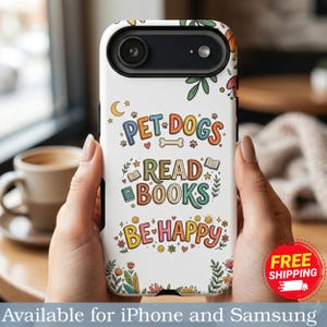 May include: A white phone case with a floral design and the text "PET DOGS READ BOOKS BE HAPPY". The case has a black camera lens and is held by a person. The case is available for iPhone and Samsung.