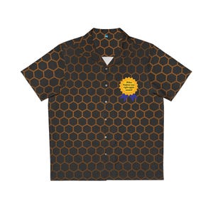 May include: A short-sleeve button-down shirt featuring a dark gray and brown honeycomb pattern. On the left chest, there is a yellow circular award badge with blue ribbons and the text Hideo Kojima was right again award printed in black.