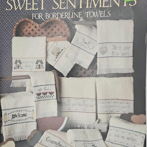 May include: A collection of white borderline towels with cross-stitched designs and phrases like "Welcome," "Bless your little heart," and "Love one another." The towels feature various motifs, including houses, watermelons, and angels. The leaflet title is "Sweet Sentiments."