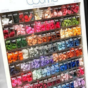 May include: A display of Cosmo embroidery cotton in various colors. The display includes a range of thread colors, from white and pastels to vibrant hues. The text "Cosmo Embroidery Cotton" is visible at the top.