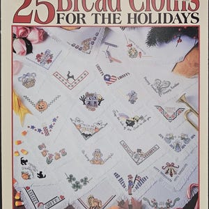 May include: A leaflet titled "25 Bread Cloths for the Holidays" by Leisure Arts. The cover features a collection of embroidered bread cloths with holiday-themed designs, including pumpkins, flags, and Easter eggs. The price is $3.50.