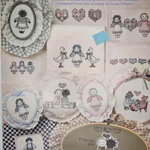 May include: A collection of cross-stitch designs featuring dolls, hearts, and geese. The designs are displayed in various oval and circular frames, with the text "Sarah Jane's Friends" at the top. The color palette includes pink, blue, and white.