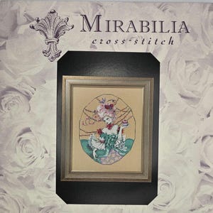 May include: A framed cross-stitch piece featuring a woman in a period costume holding a small cake. The artwork is set against a background of roses and the text "Mirabilia cross-stitch" is visible at the top.