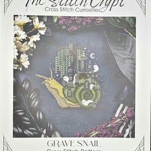 May include: A cross-stitch pattern titled "Grave Snail" featuring a whimsical design. The image showcases a snail with a haunted house shell, accompanied by ghosts. The text "The Stitch Crypt" and "Cross Stitch Curiosities" are also visible.
