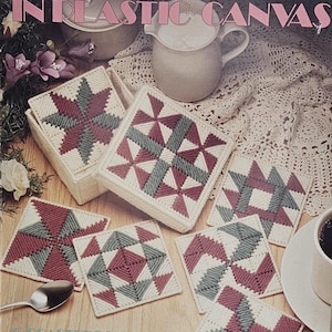 May include: A collection of handmade patchwork coasters in a variety of geometric designs, featuring red, gray, and white stitching. The coasters are displayed with a matching box, a spoon, and a cup of coffee. The text on the cover reads "Patchwork Coasters in Plastic Canvas."