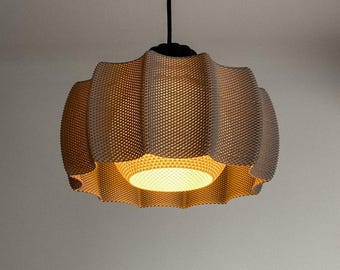 May include: A beige, textured pendant light fixture with a unique, wavy design. The light hangs from a black cord and fixture. The interior of the lamp is illuminated with a warm, inviting glow, creating a soft ambiance. The lamp's dimensions are not visible.