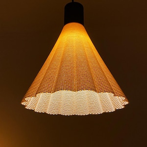 May include: A hanging pendant light with a woven, cone-shaped shade. The shade is a warm yellow color, and the light source is visible at the bottom. The fixture has a black top and a black cord.