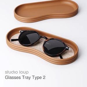 May include: A brown oval glasses tray with a textured surface, holding a pair of sunglasses with black lenses and a tortoiseshell frame. The tray is labeled "Glasses Tray Type 2" with the studio name "studio loup".