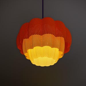 May include: A hanging pendant light fixture with a layered design. The top layer is a vibrant red-orange, transitioning to a warm orange, and finally a bright yellow at the bottom. The textured surface is covered in small, evenly spaced bumps.