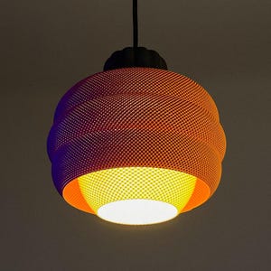 May include: Orange and purple pendant light fixture with a textured, spherical shade. The light has a black cord and a bright, warm light emanating from the bottom. The shade has a unique, patterned design.