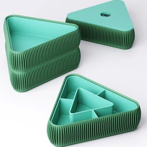 May include: A set of three triangular storage containers with a ribbed dark green exterior and a smooth light mint green interior. One container is divided into four sections, one is open, and one is shown with its matching triangular lid.