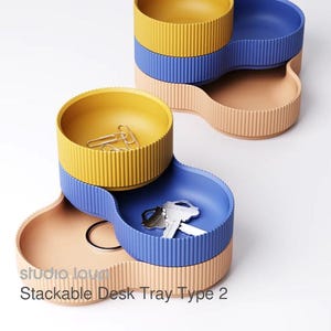 May include: Stackable desk tray type 2 in yellow, blue, and peach. The desk organizer has a ribbed texture and holds paper clips and keys. The Studio Lou logo is visible.