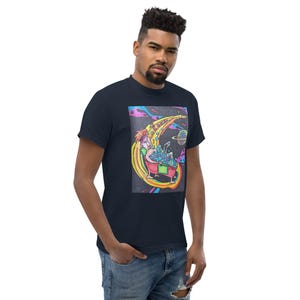 May include: Navy blue t-shirt featuring a colorful graphic of a person in a bathtub with bubbles, a crescent moon, and a planet. The word "BATHES" is written in a curved design above the person. The artwork has a cartoonish style with bright colors.