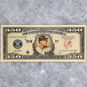 May include: A novelty bill featuring Aaron James Judge of the New York Yankees. The bill is tan with black and green text, and a portrait of Judge in a baseball uniform. The text reads "Three Hundred and Fifty Home Runs."