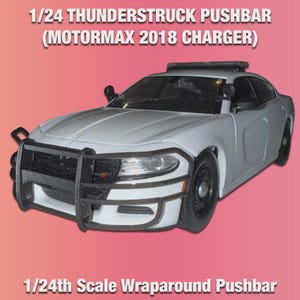 Op de afbeelding: Een wit 1/24 schaalmodel van een politieauto met een zwarte pushbar en wraparound design. Het model is een MotorMax 2018 Charger. De tekst op de afbeelding luidt "1/24 Thunderstruck Pushbar" en "1/24th Scale Wraparound Pushbar".